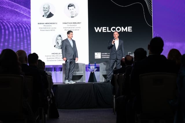 Two speakers welcoming attendees on the main stage at the INSPIRE luxury hospitality event.